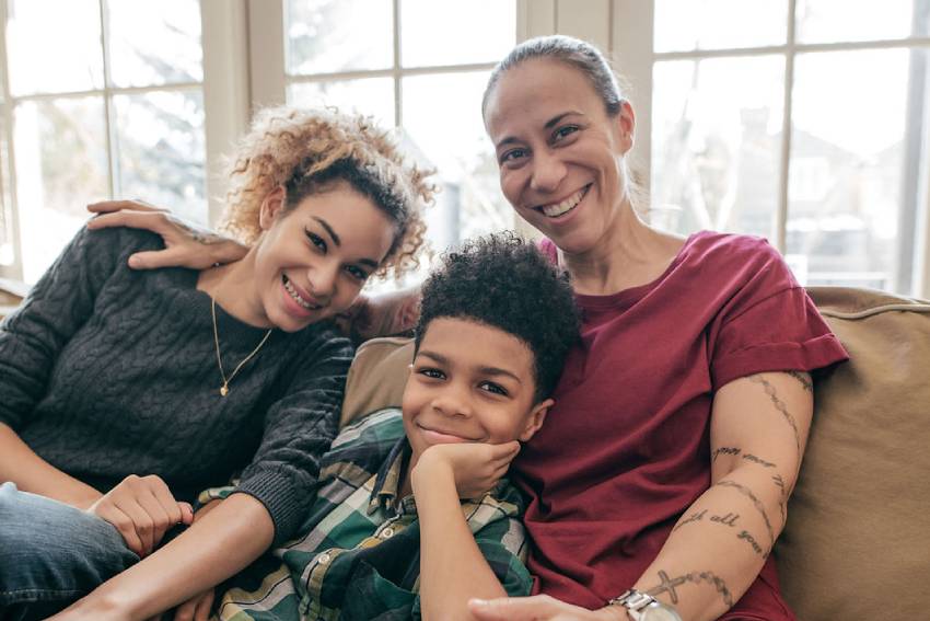 Two women and a boy sitting on a brown couch